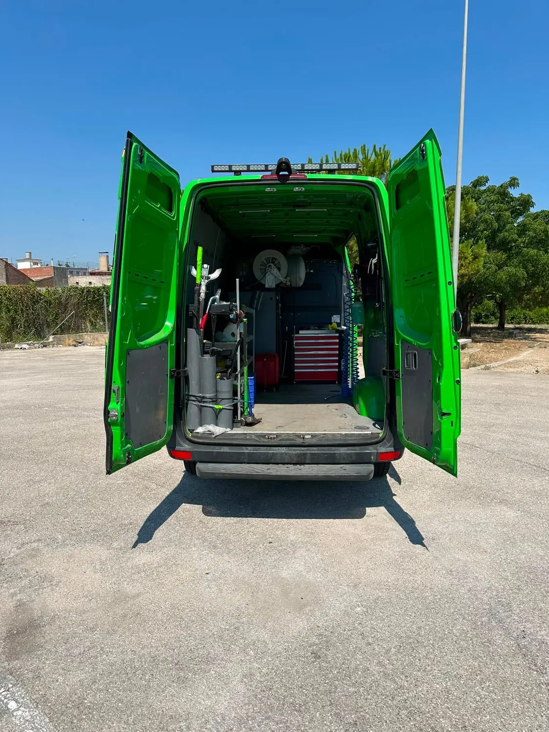 Interior de la furgoneta por las puertas traseras: enrolladores de aire, gatos, carro de herramienta y equipo de neumáticos