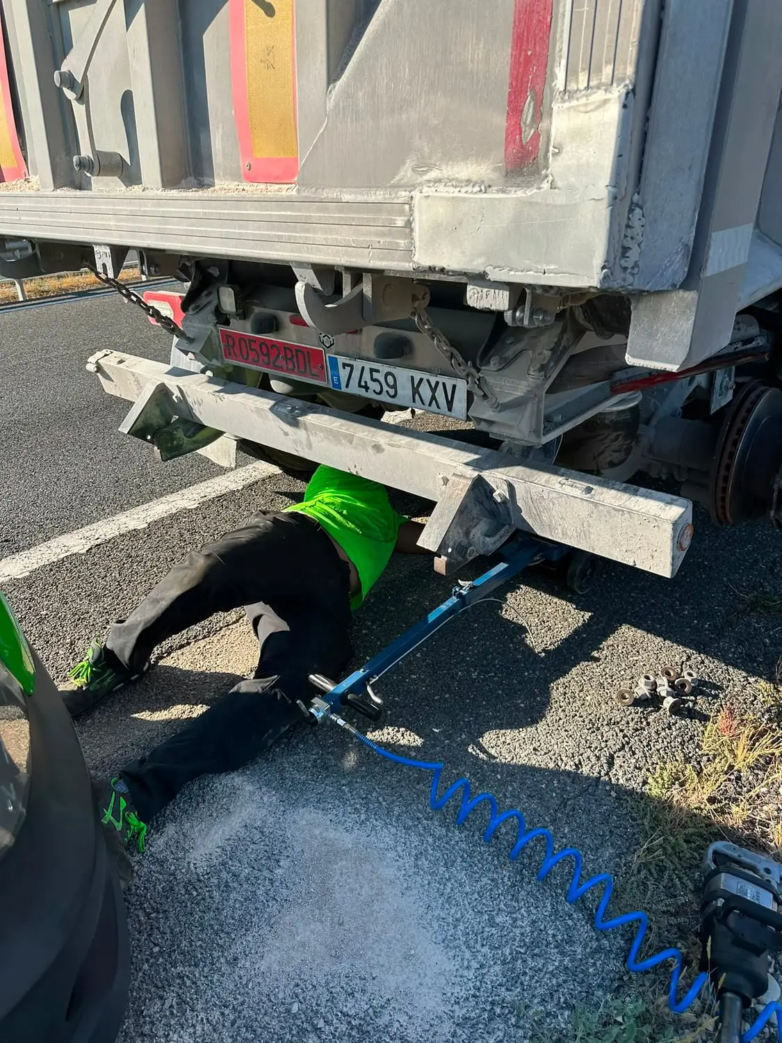 Mecánico trabajando bajo un semirremolque con gato hidráulico y línea de aire comprimido