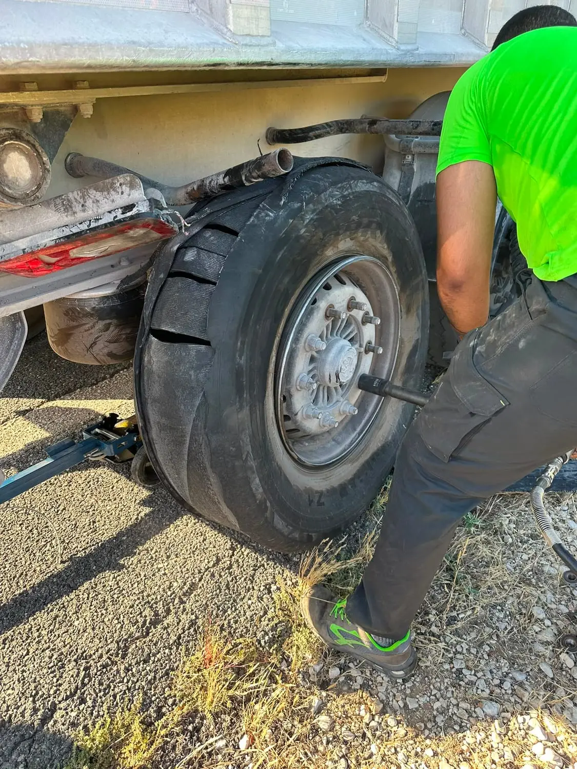 Mecánico de ZAC TRUCK desmontando con pistola de impacto un neumático de camión reventado en plena carretera